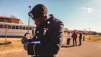 A veteran in uniform writing thoughtfully in a journal, with a textured steel-blue military backdrop.