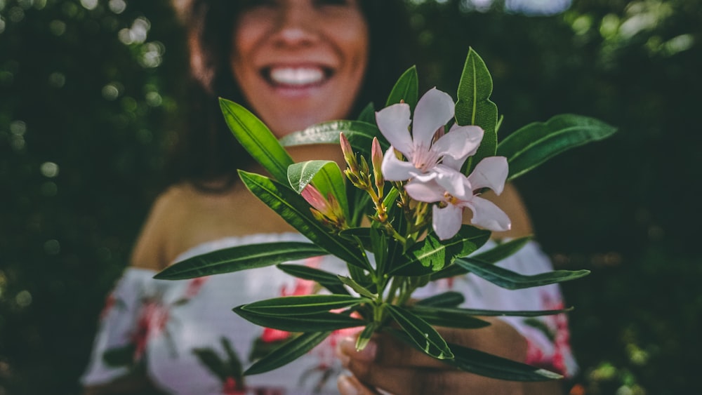 woman holding white petaled flowers