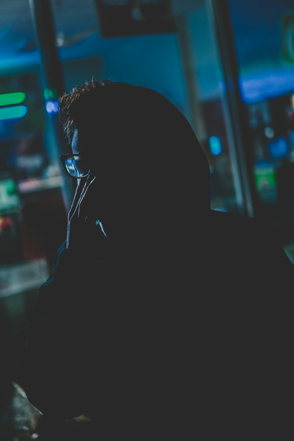 man with pair of black eyeglasses and hoodie in dark room