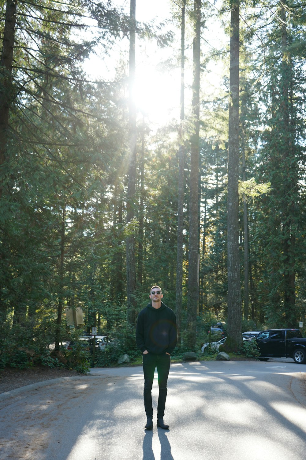 man wearing black jacket standing across forest during daytime