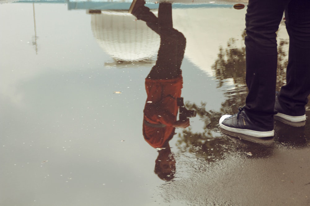 person in black pants standing on body of water