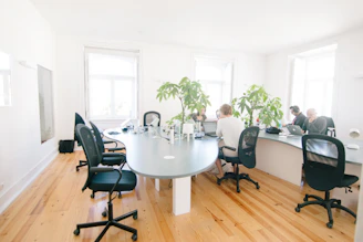 A diverse group of professionals collaborating in a bright, modern office space filled with plants and natural light.