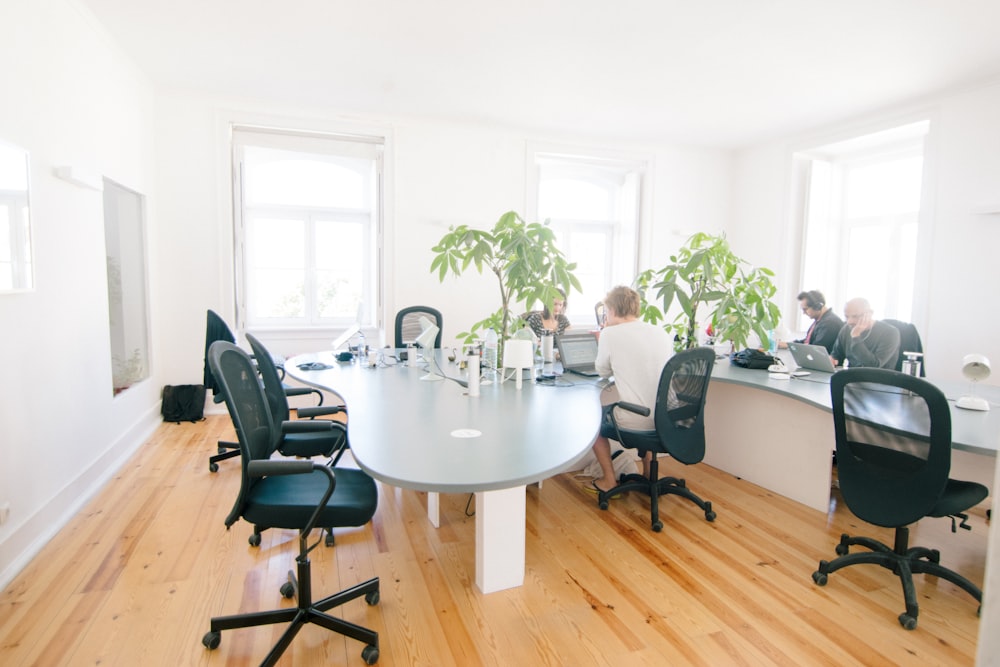 grey wooden table and black leather rolling chairs