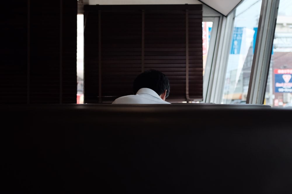 person wearing white dress shirt sitting on brown bench