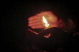 Close-up of hands holding a glowing candle symbolizing inner light and hope.