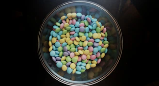 Close-up of colorful traditional hard candies arranged in a rustic wooden bowl.