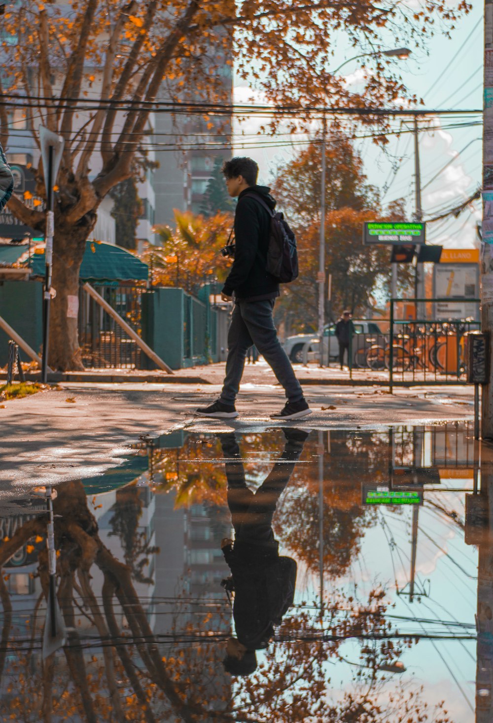 man wearing black jacket walking besides wet floor