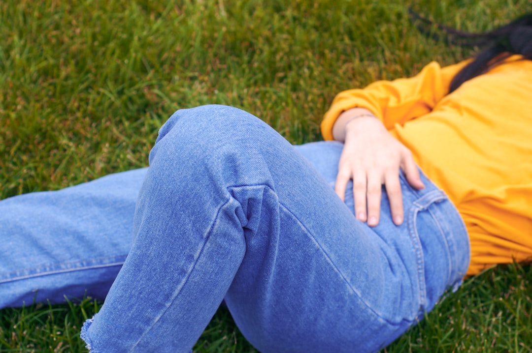 person lying on green grass wearing blue denim jeans