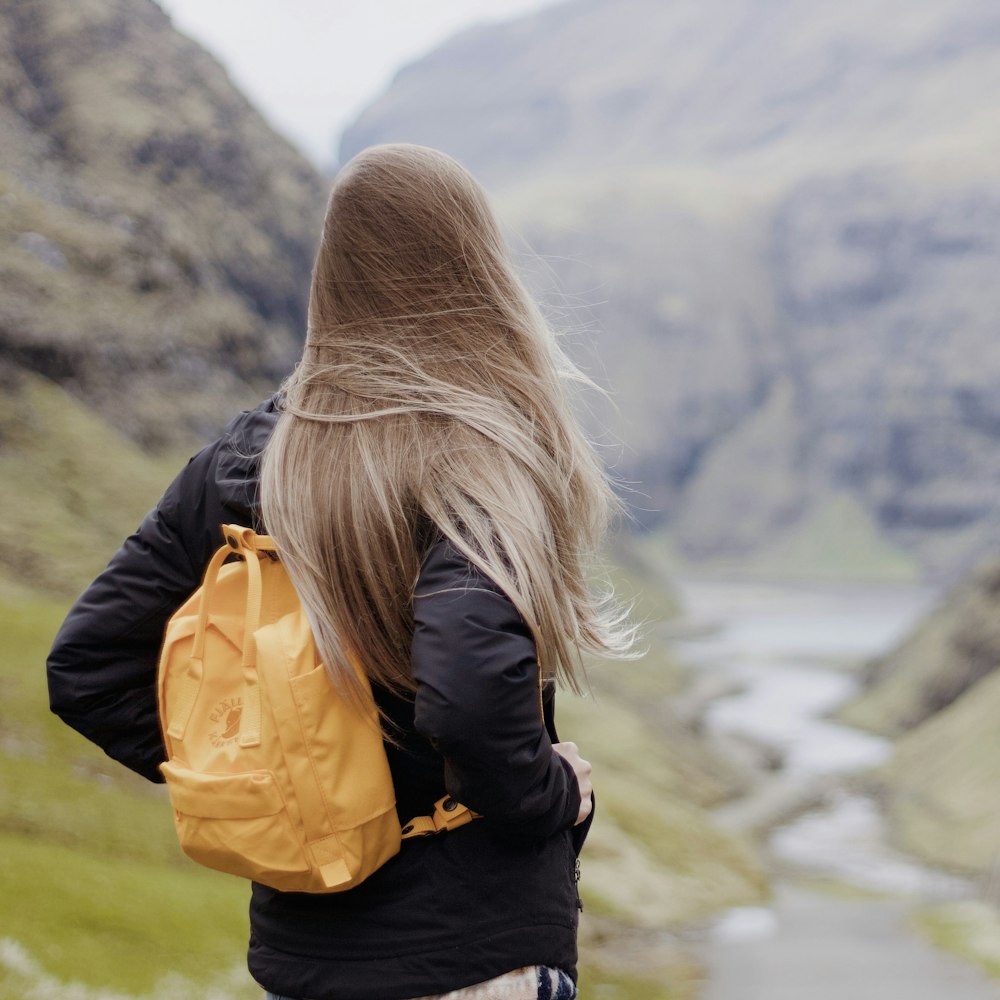 Foto Mujer con mochila amarilla mirando el río – Imagen Vestir gratis en  Unsplash