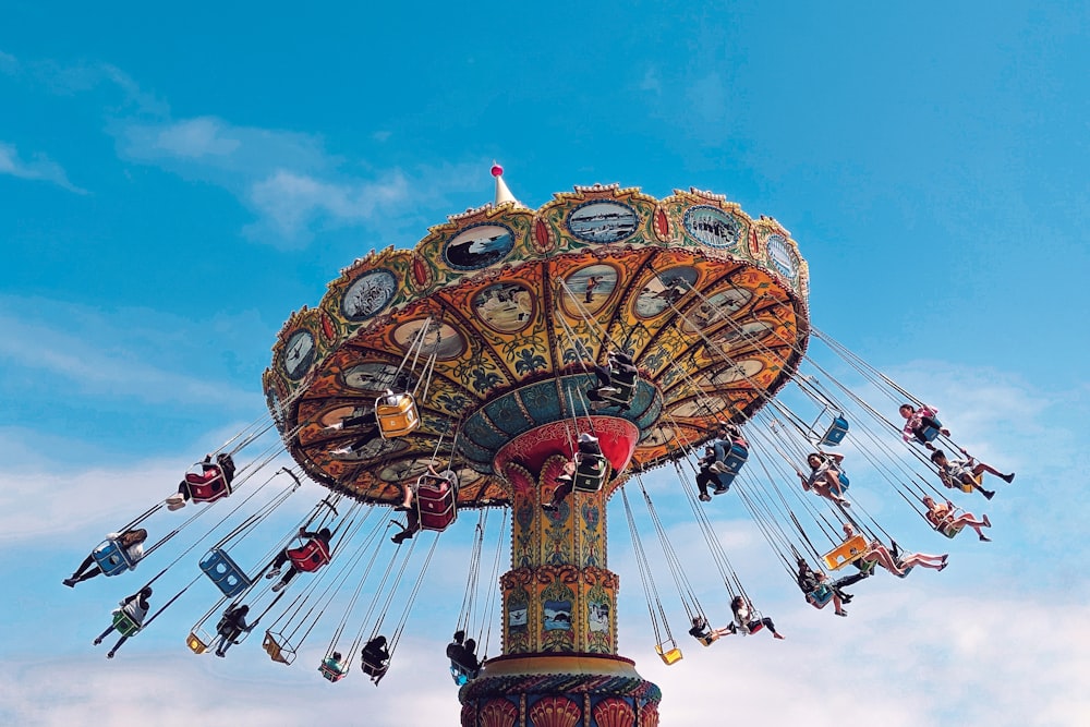 people rides on carousel during daytime