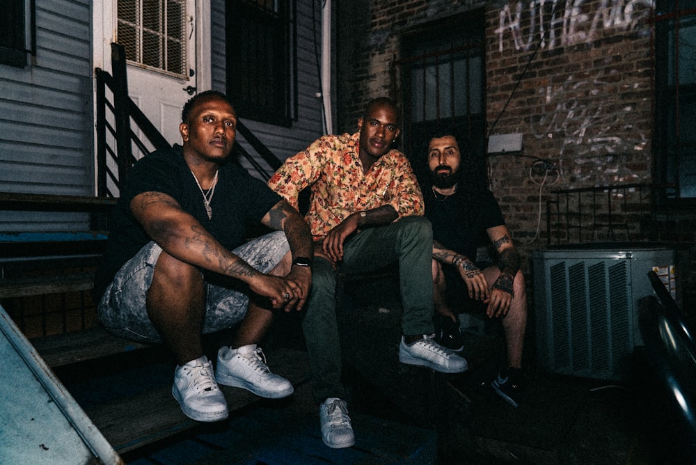 three men sitting on staircase