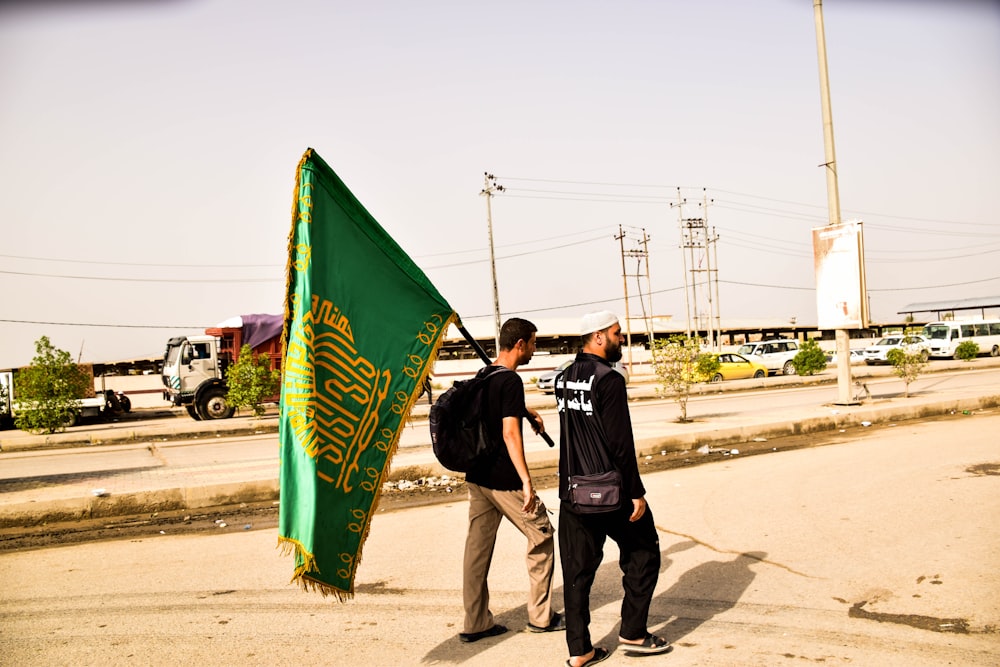 two person, one holding a green flag during daytime