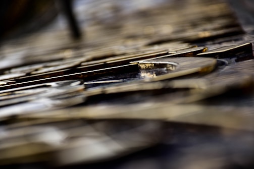 Close-up view of metallic letters arranged in a pattern. The focus is shallow, highlighting the texture and sheen on the surface of the letters. Background elements are blurred, creating a bokeh effect.