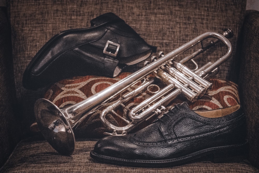 brass-colored trumpet beside black leather dress shoes
