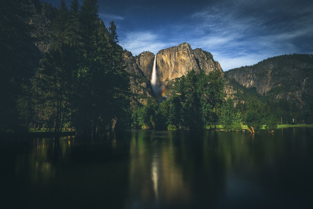 a waterfall in the middle of a lake surrounded by trees