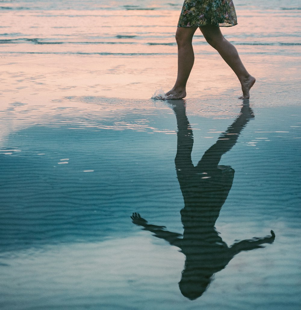 woman walking on body of water beside shore during daytime