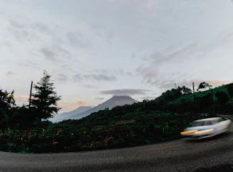 A private shuttle van driving through lush Costa Rican rainforest with volcano in the background.