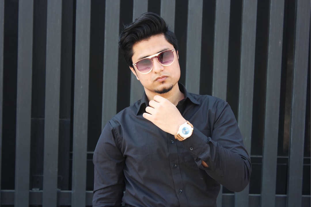 man wearing black dress shirt showing gold-colored watch,