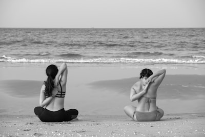 grayscale photography unknown persons seating near body of water