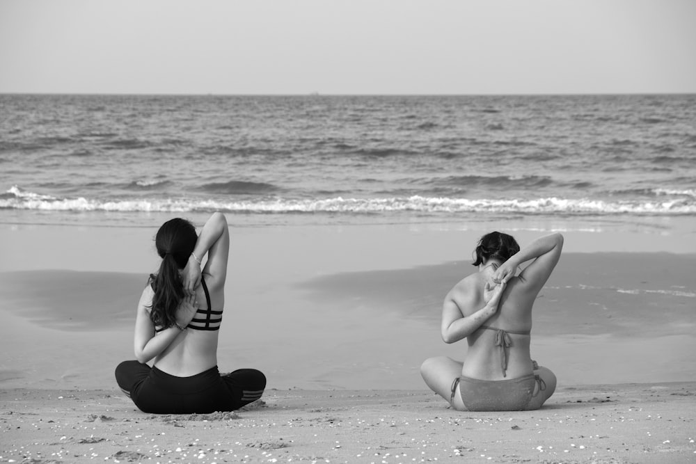 grayscale photography unknown persons seating near body of water