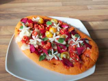 A vibrant plate of fusion pizza-prata topped with fresh herbs and spices.