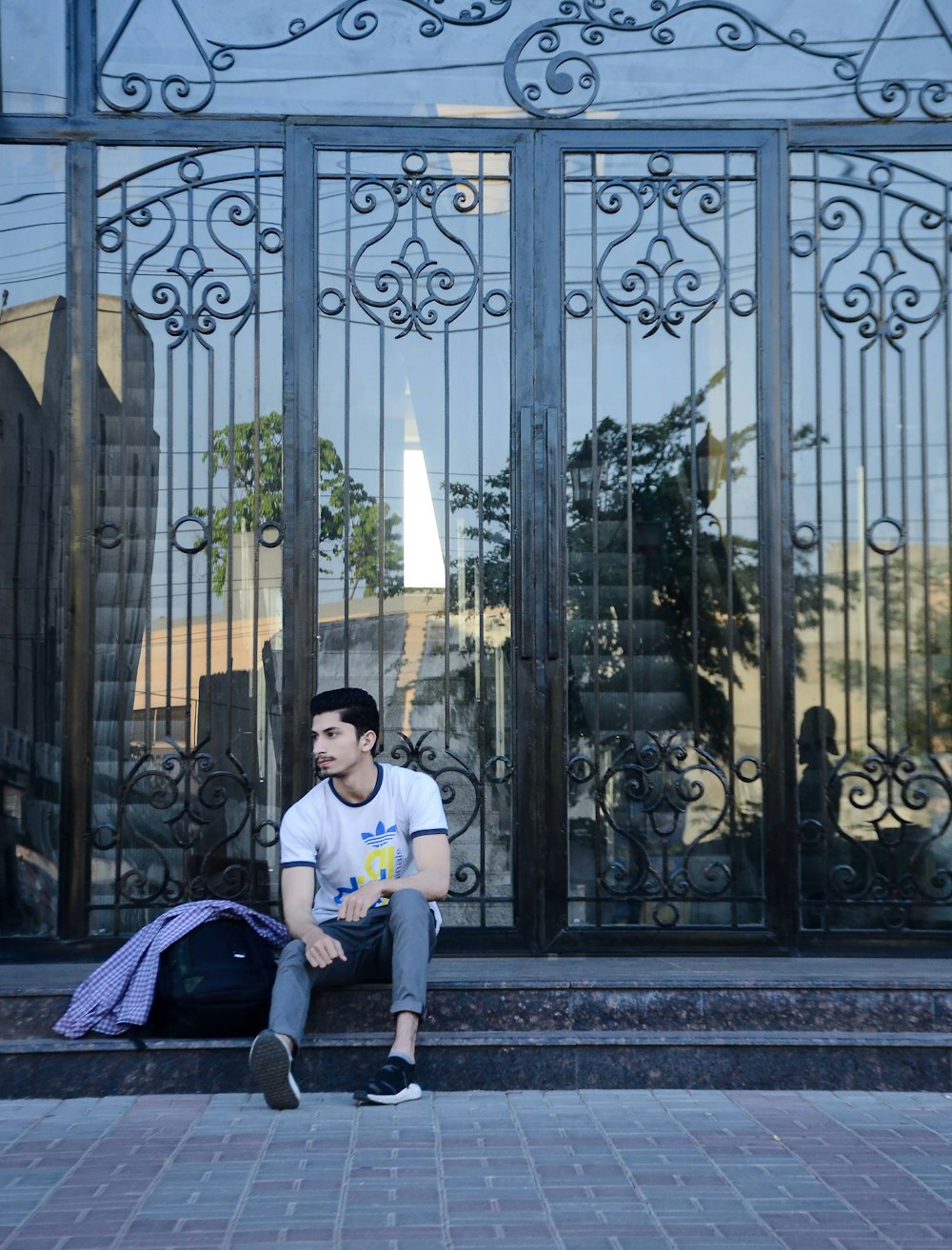 man sitting beside metal gate during daytime