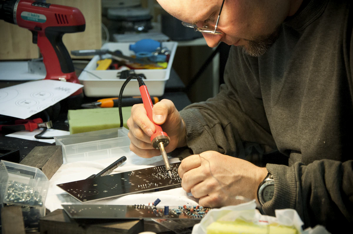 A technician soldering a circuit board at a workbench