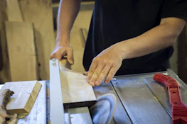 Workers handling wooden planks in a busy sawmill environment.
