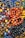 A collection of various colorful beads, some made into bracelets, with a glossy and reflective surface. The beads are arranged in a dense pile, showcasing a wide array of colors and sizes, including shades of orange, black, brown, yellow, blue, and gray.