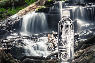 A clear bottle of Yara Fresh water resting on a wooden table with a backdrop of lush green hills.