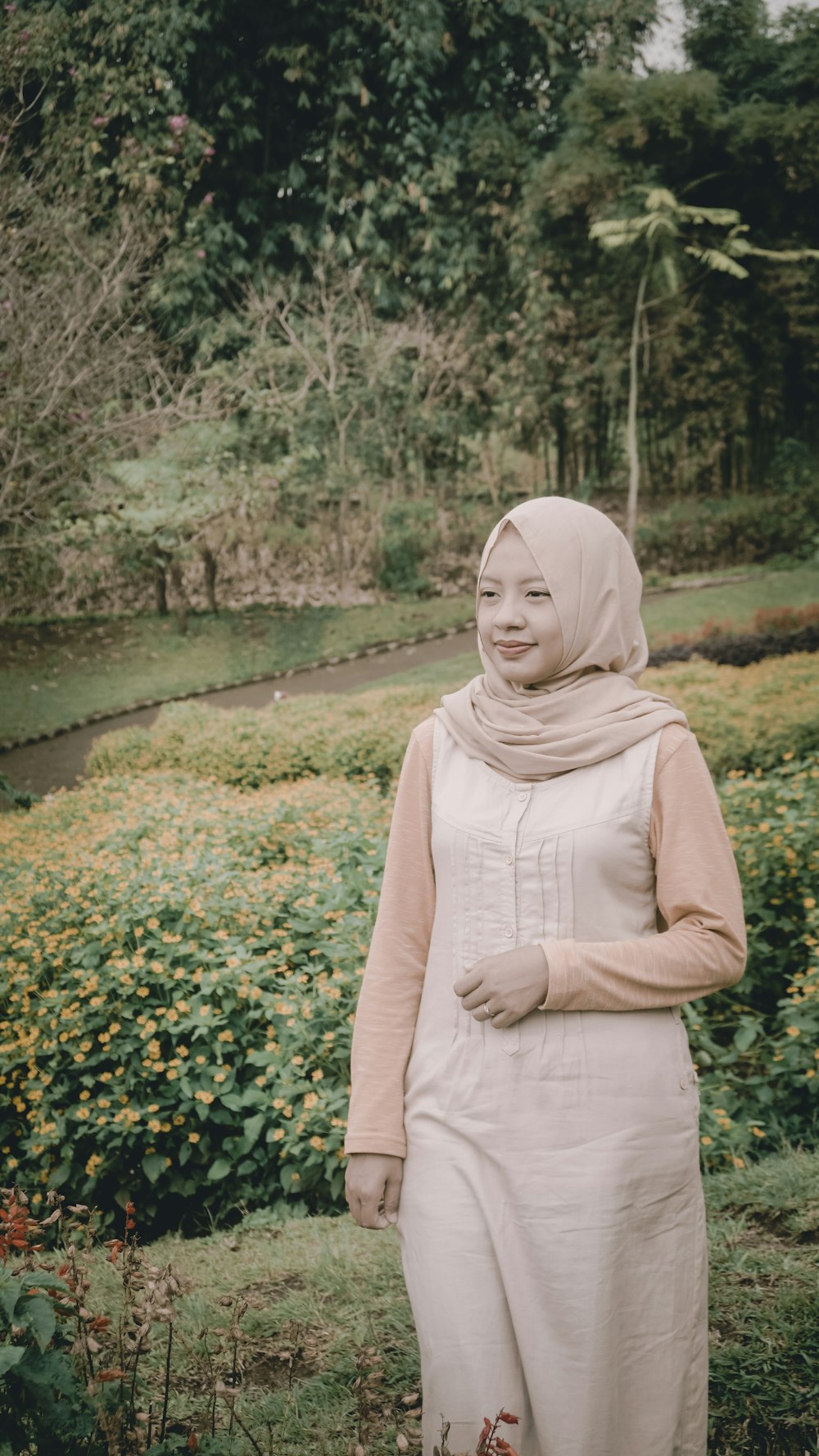 woman walking wearing abaya dress near hedges