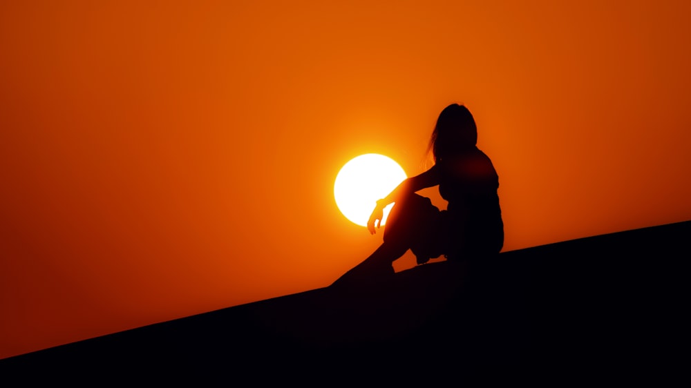 silhouette of woman sitting on ground