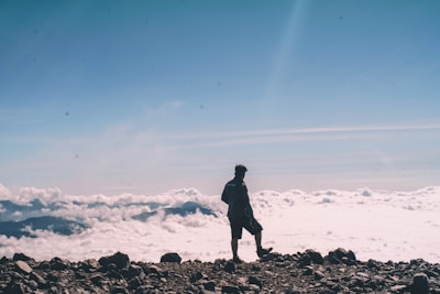 An individual standing on a mountain peak, looking towards the horizon.