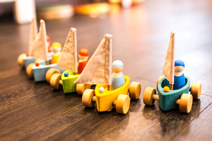 Handmade wooden toy sailboats lined up on a warm wood floor