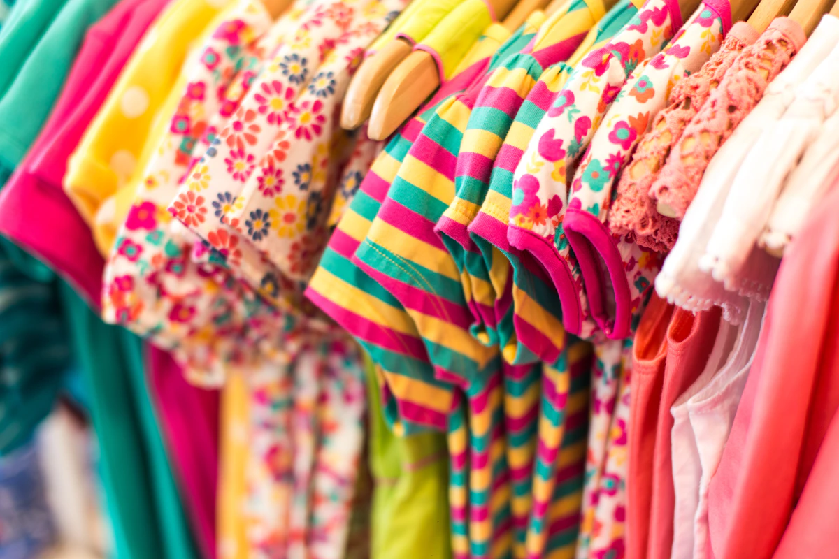 Colourful traditional children's clothing with embroidered details displayed on a rack