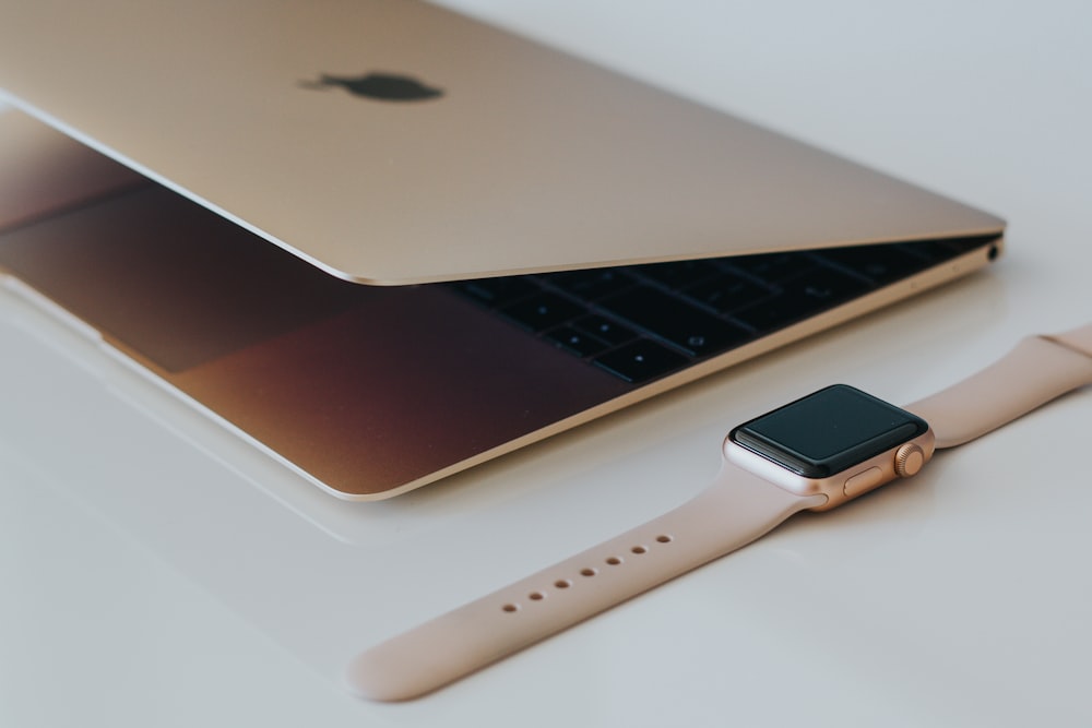 caja dorada Apple Watch junto a MacBook plateado