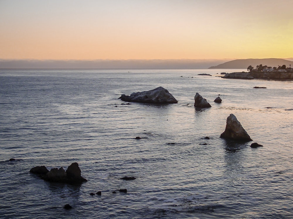 rock formations on sea under orange skies