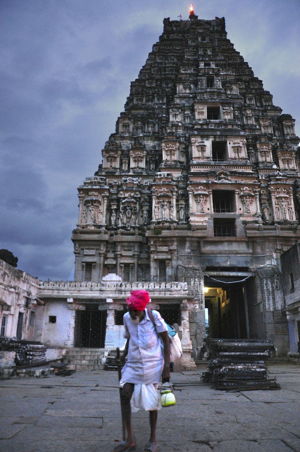 man in white kurta walking in front of beige building