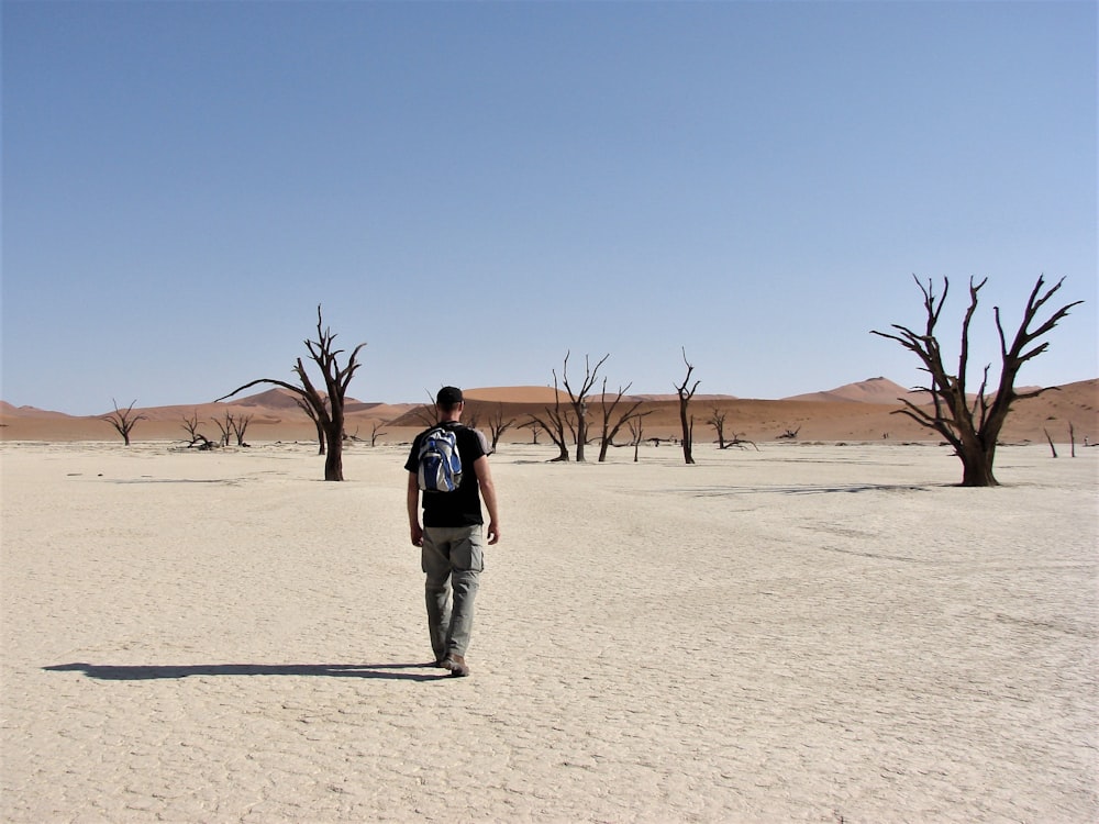 walking man wearing black shirt near bare trees