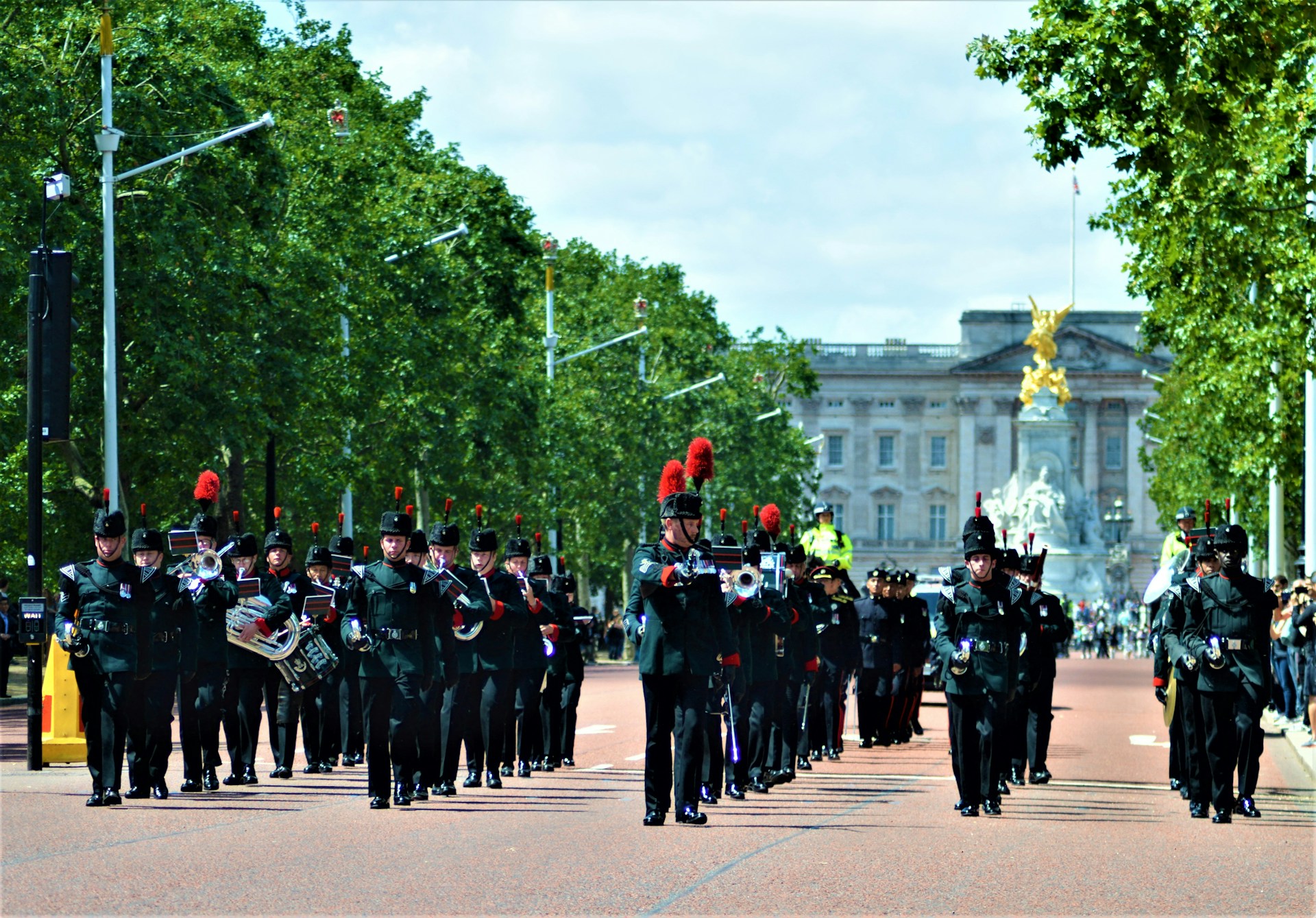 The full drumline marching in formation on the school field, the wolf mascot banner waving proudly in the background.