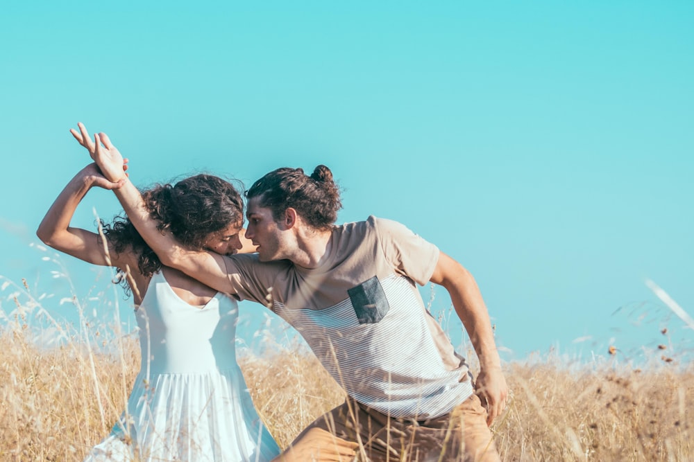 man and woman dancing in brown grass field