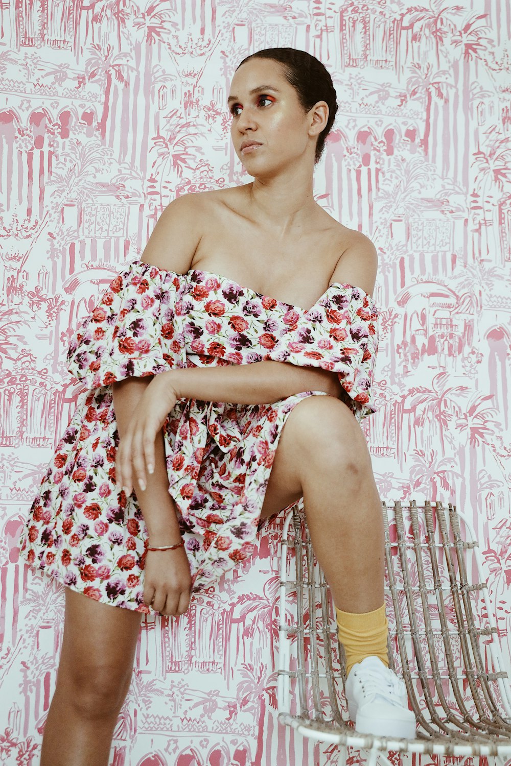 woman wearing floral off-shoulder romper with her right foot on chair