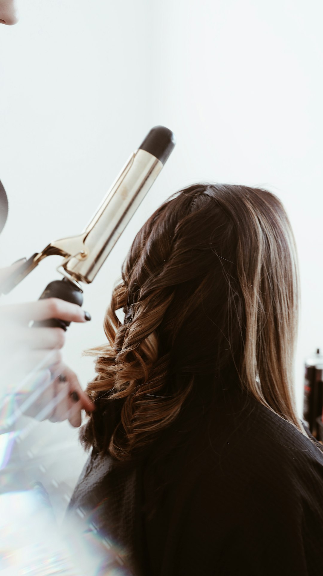 curling iron and a woman getting her hair styled with a curling iron