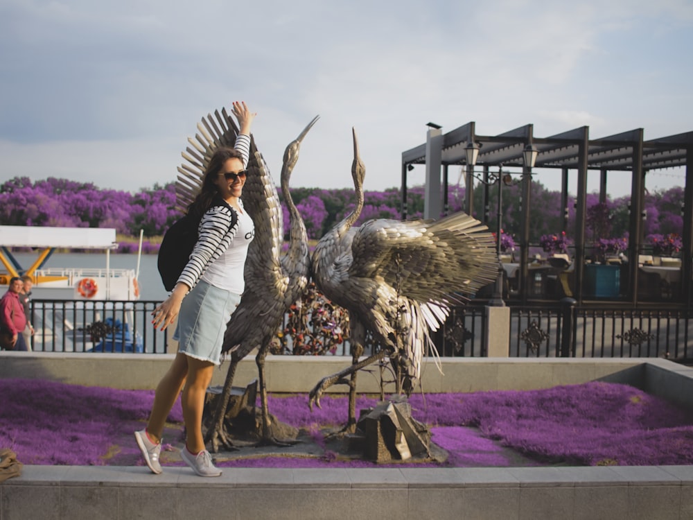 woman standing beside two bird statues