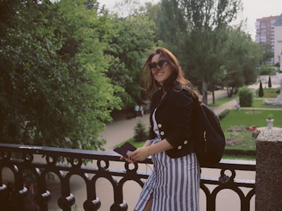 A fashionable woman in dbl-electronique apparel, smiling while working on an electronic project outdoors in a vibrant urban park.