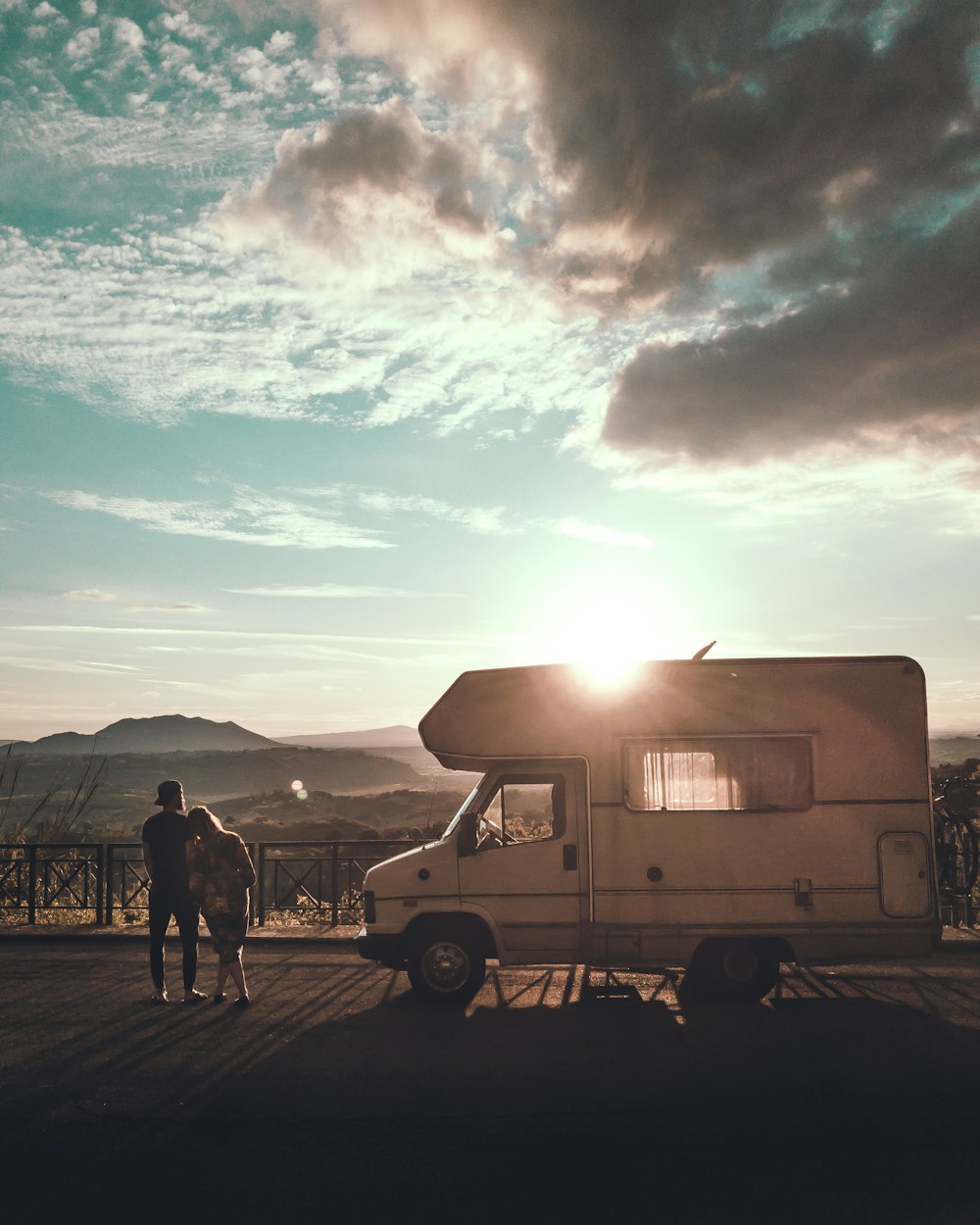 man and woman standing beside camper trailer on the street