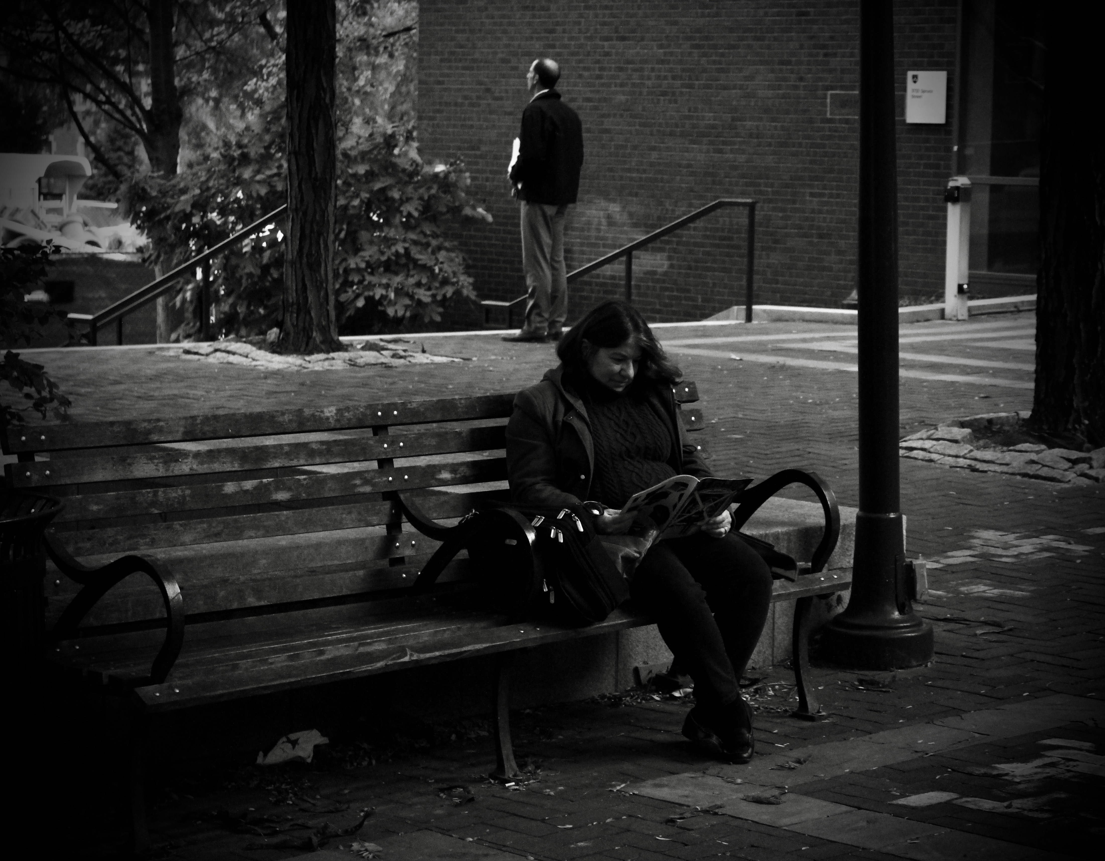 Frau sitzt auf Bank und liest Zeitung