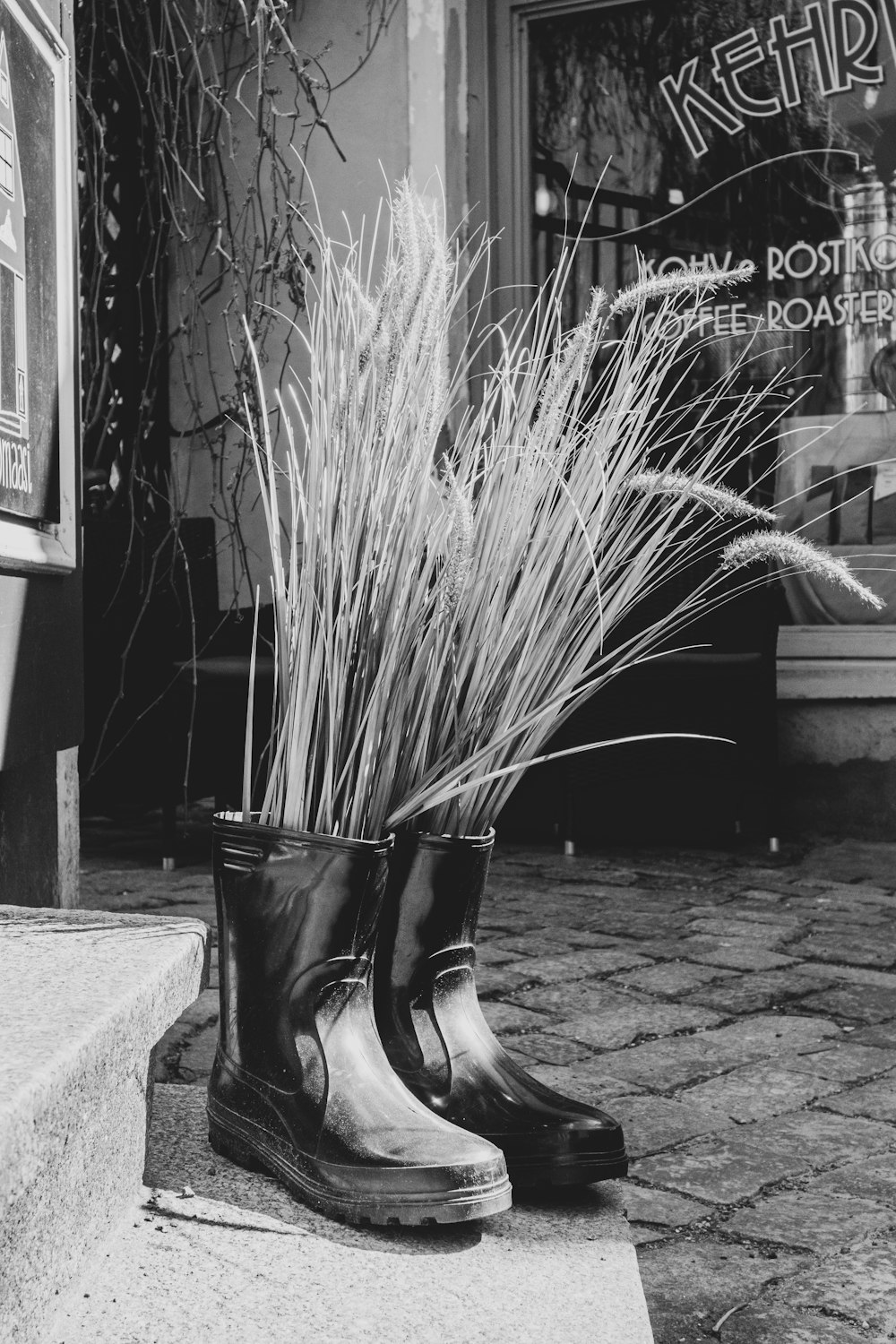 twigs inside black rain boots on pavement near stairs