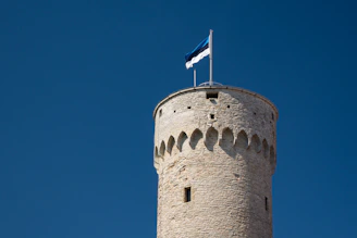 brown concrete tower with blue, black, and white flag on top