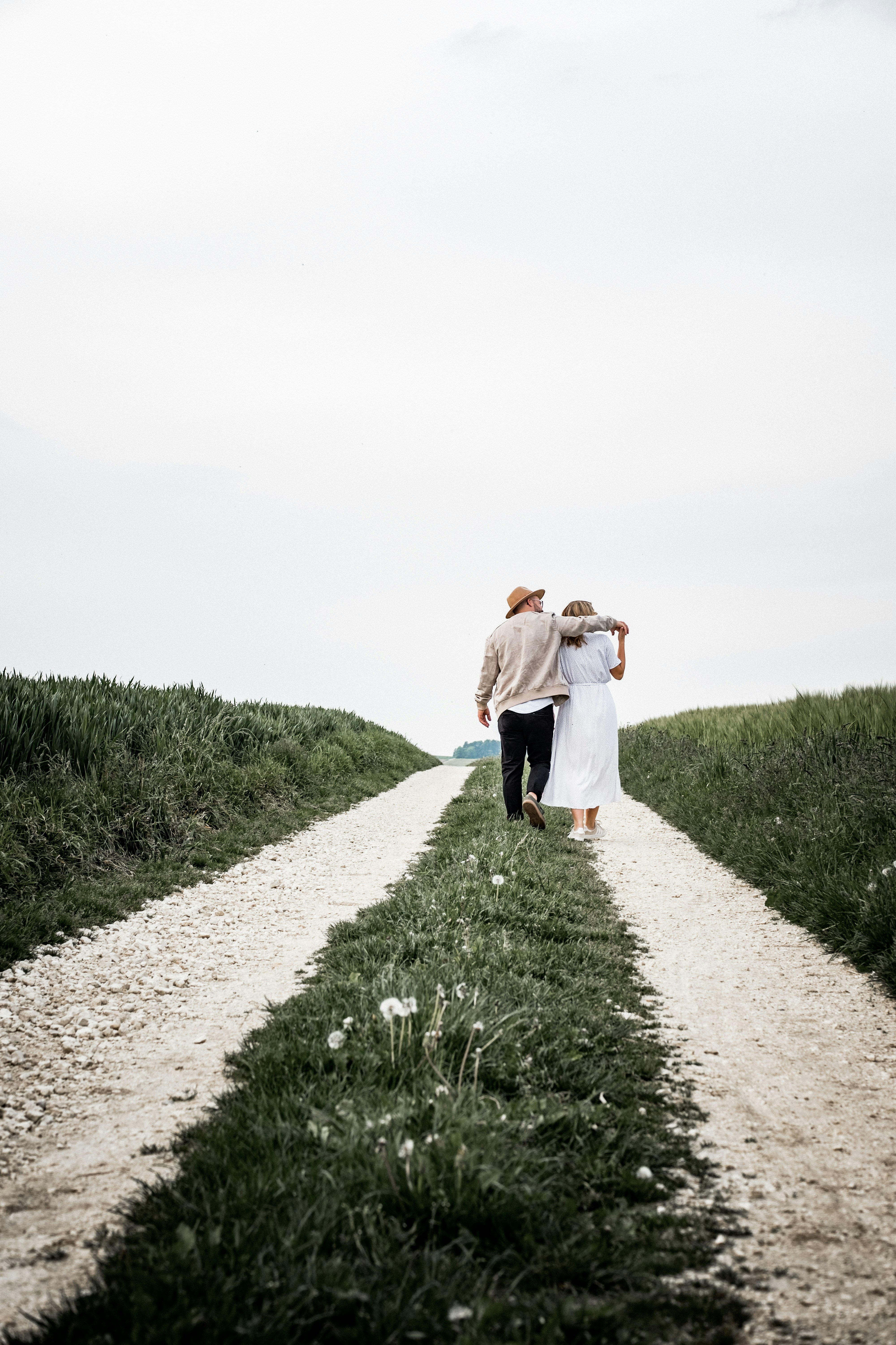 man and woman walking on pathway beside green bush